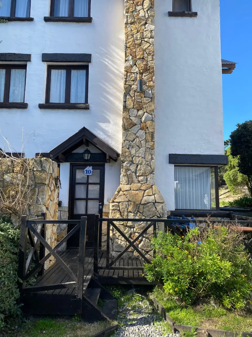 Frente de cabaña con chimenea de piedra en Puerto Delfín, Mar de las Pampas